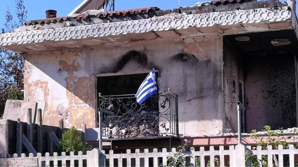 Γυναίκα ύψωσε την ελληνική σημαία στο καμένο σπίτι της στο Μάτι